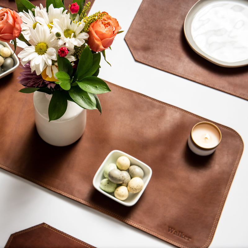 Table set with a fine leather table runner, flower, candles, and fine leather placemats